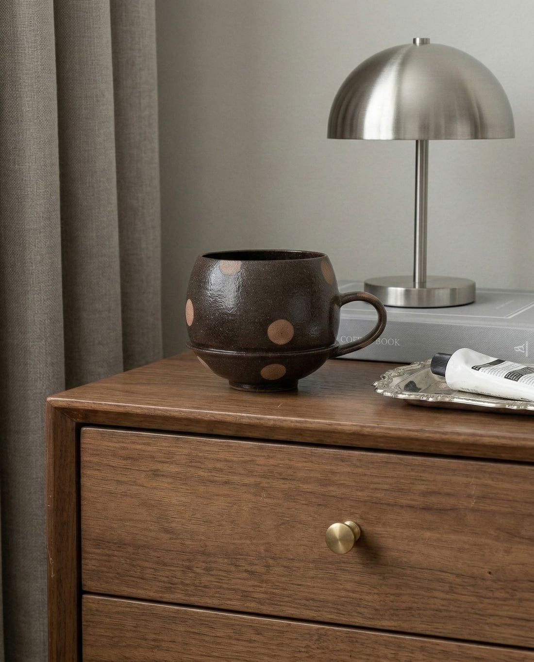 Black ceramic cup with brown polka dots on a light gray background