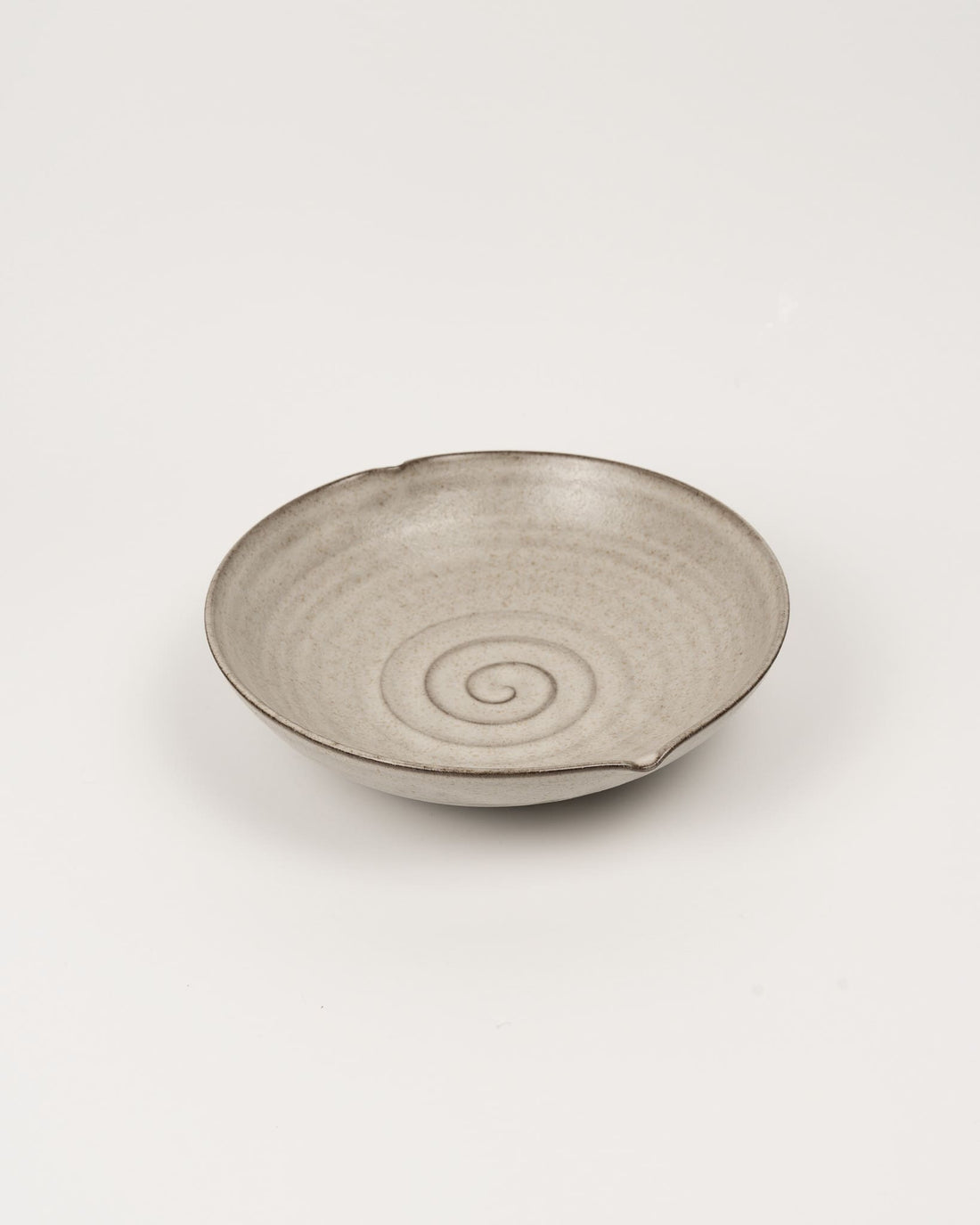 Beige ceramic bowl with a spiral design on a light beige background