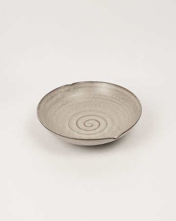 Beige ceramic bowl with a spiral design on a light beige background