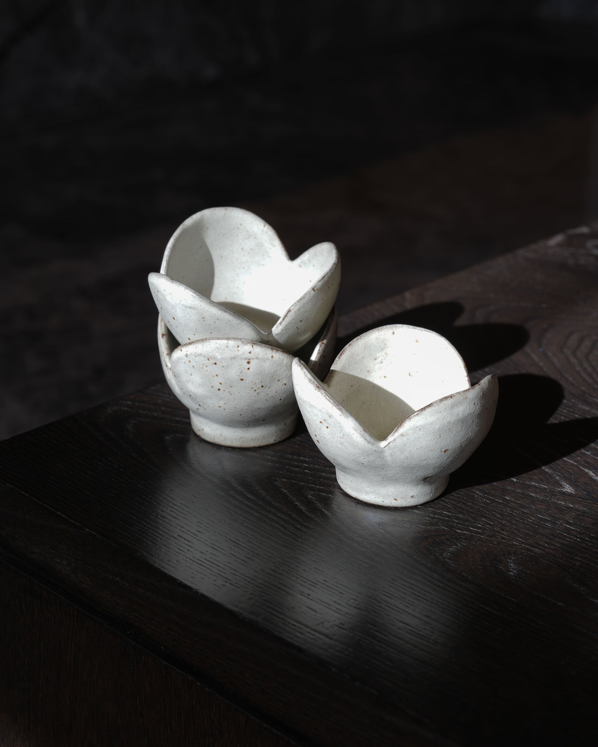 Three white ceramic bowls stacked on a dark wooden surface