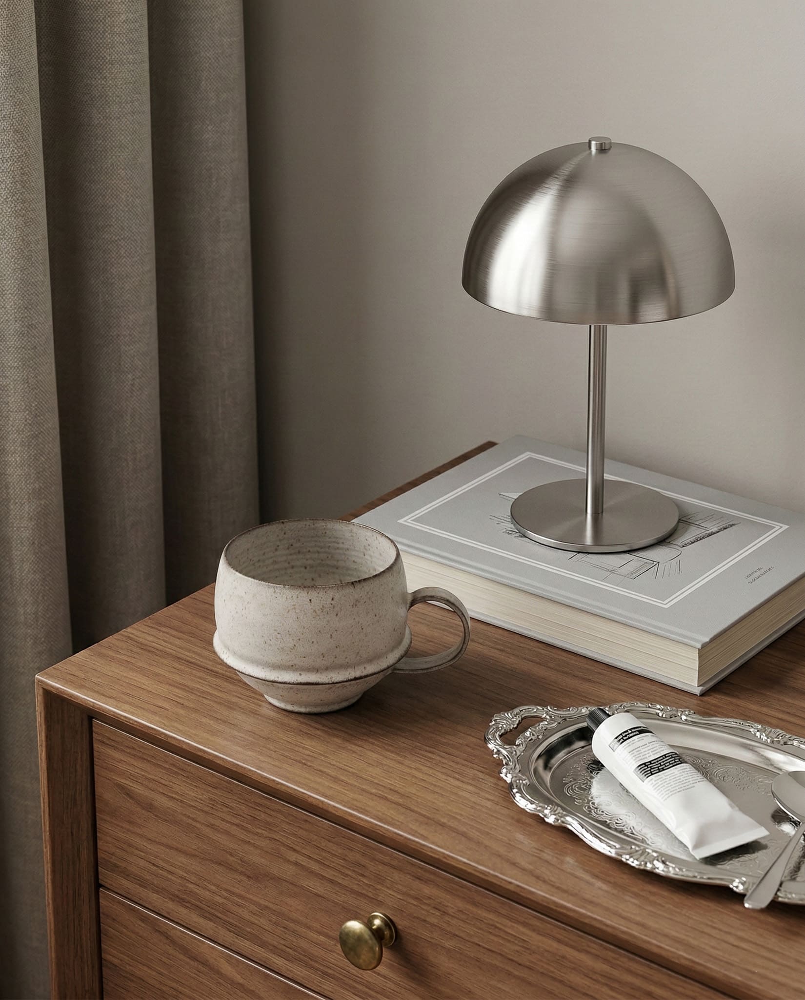 Table with a lamp, mug, book, and tray on a wooden surface.