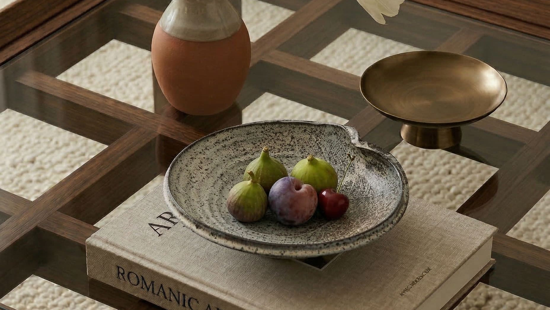 Decorative setting on a coffee table with a bowl of fruit, vase, and books.slider_item_aiJ97k