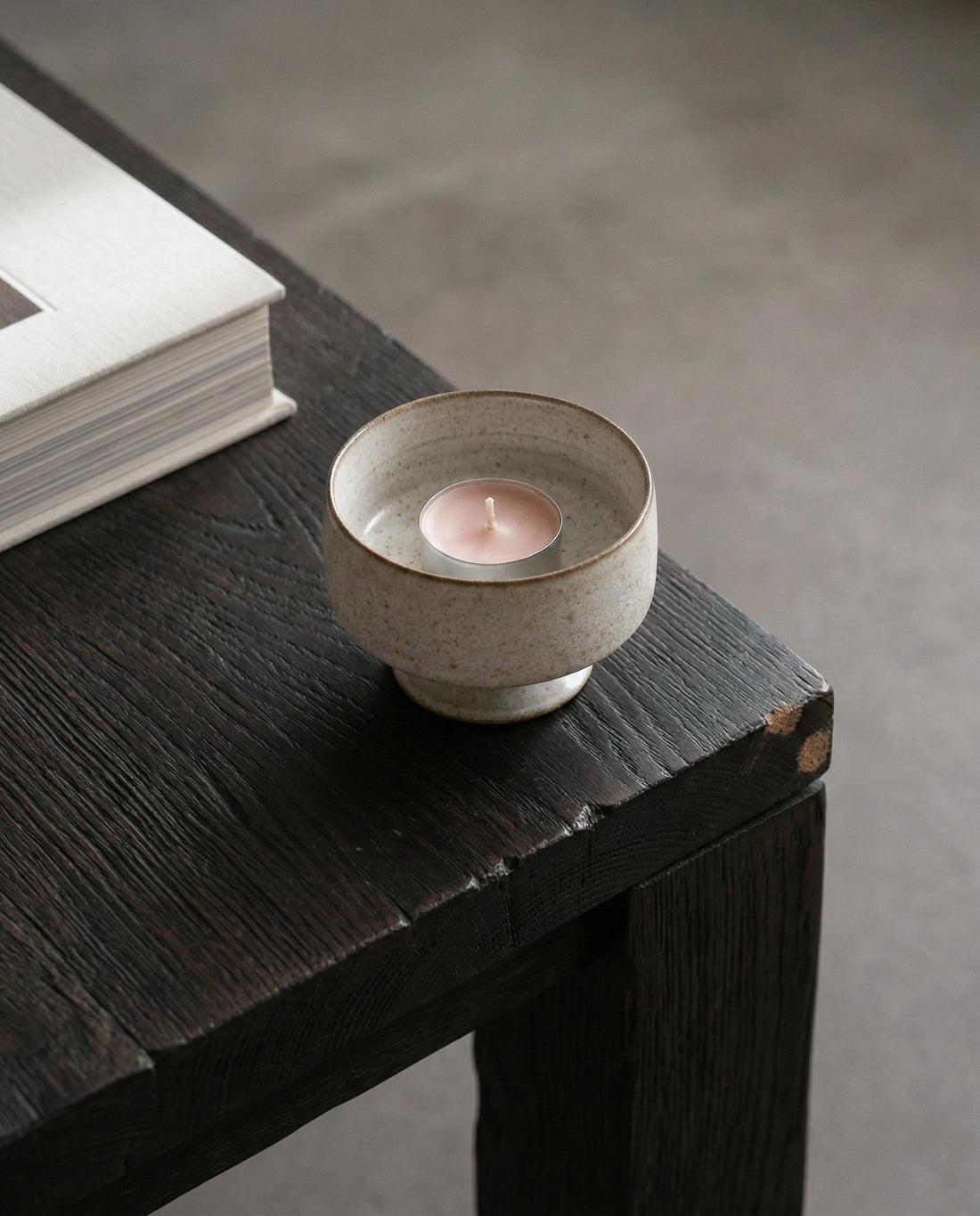 Hand placing a small candle into a ceramic holder on a light background