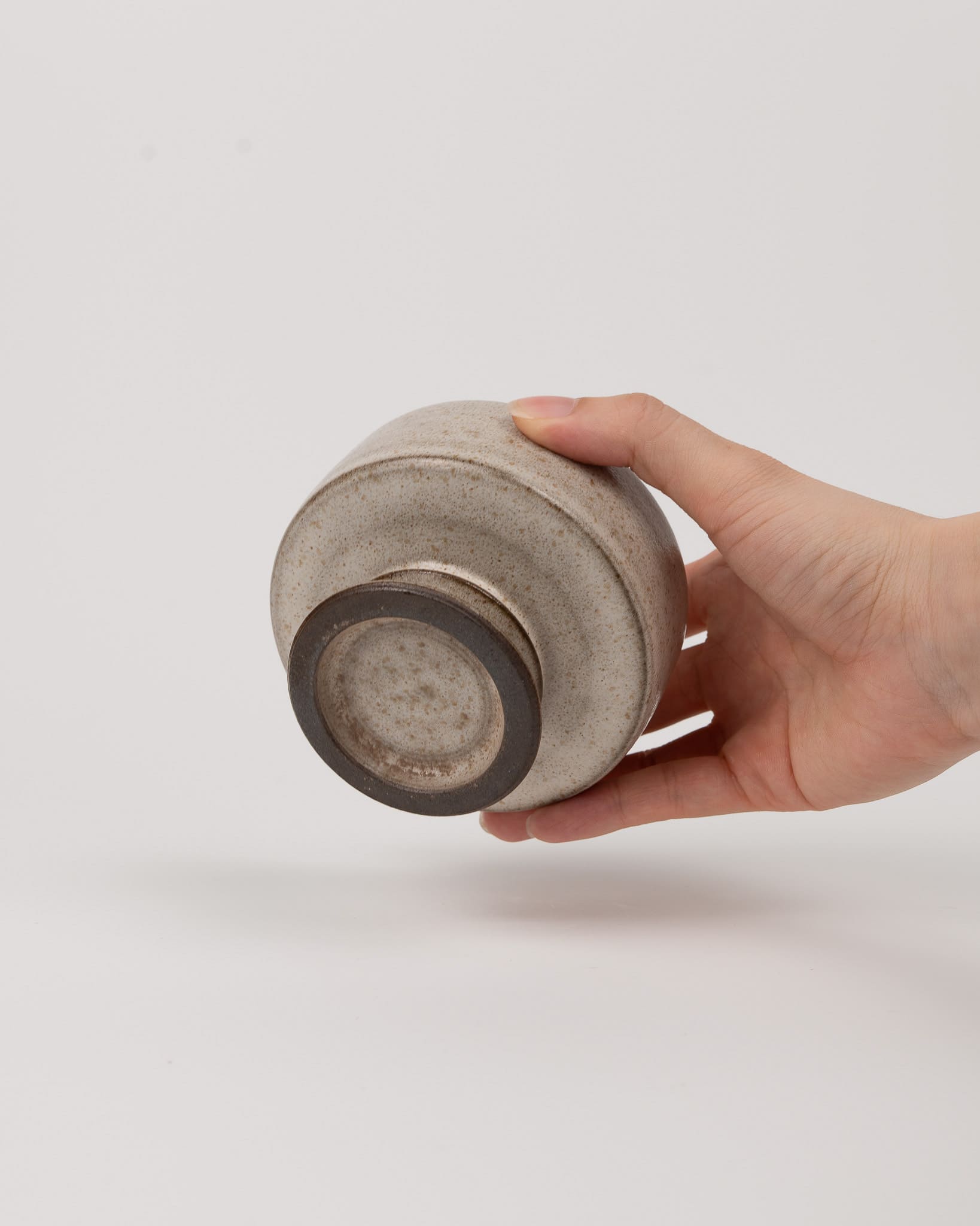 Hand holding a textured ceramic cup against a plain background