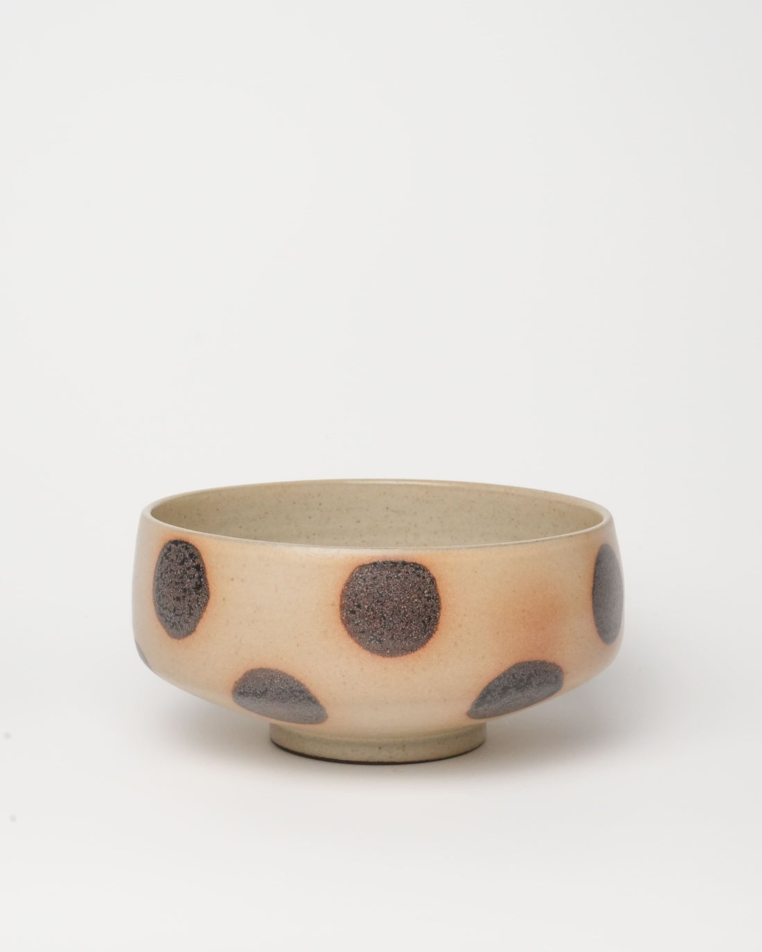 Bowl with fruits on a wooden table next to an open book, with a patterned rug underneath.