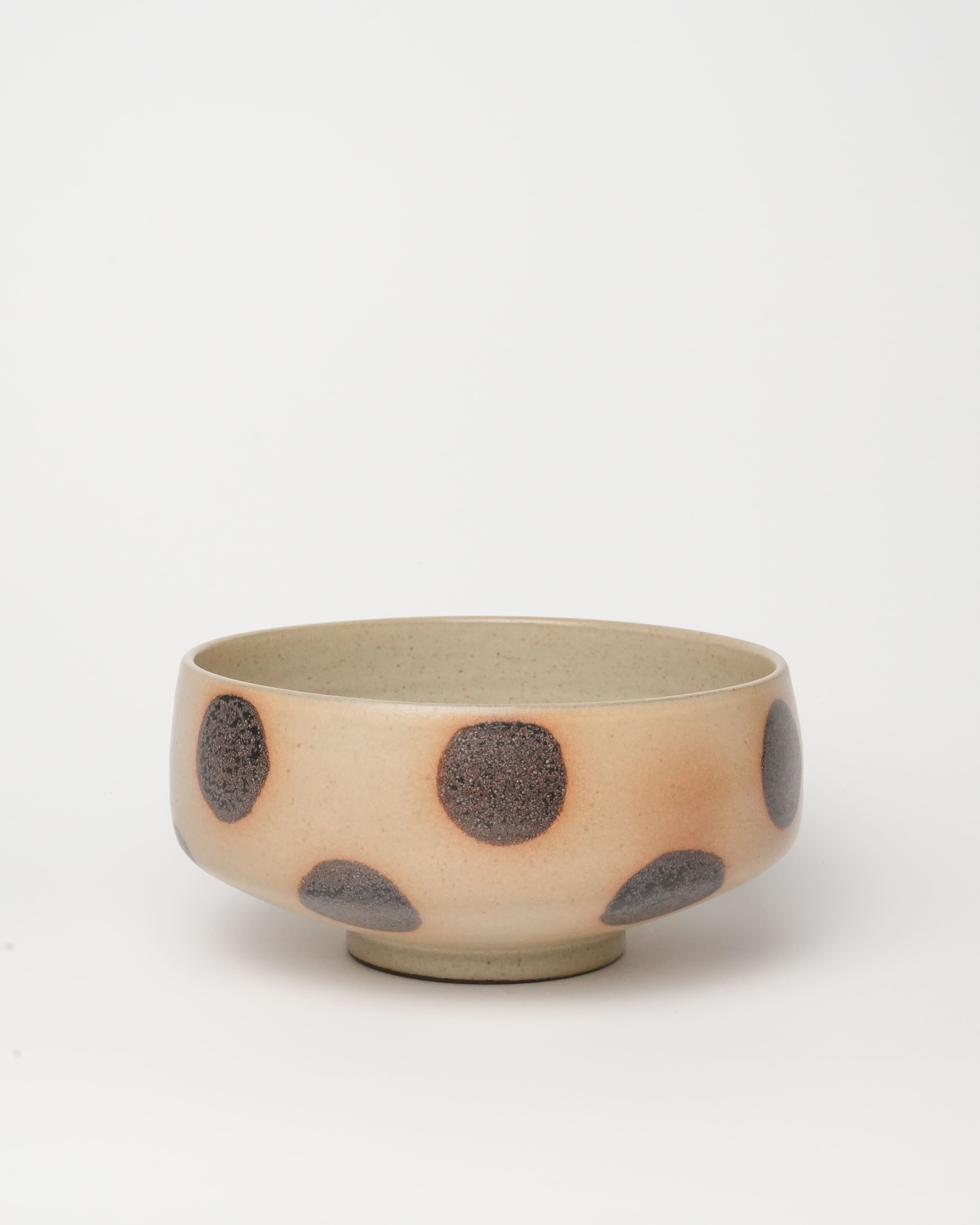 Ceramic bowl with brown polka dots on a light beige background