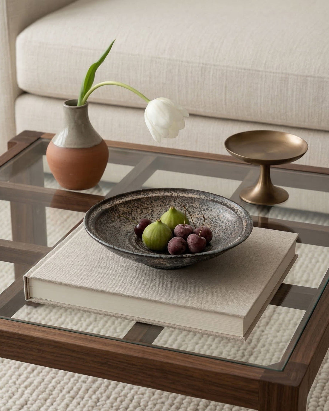 Decorative setting on a coffee table with a bowl of fruit, vase, and books.