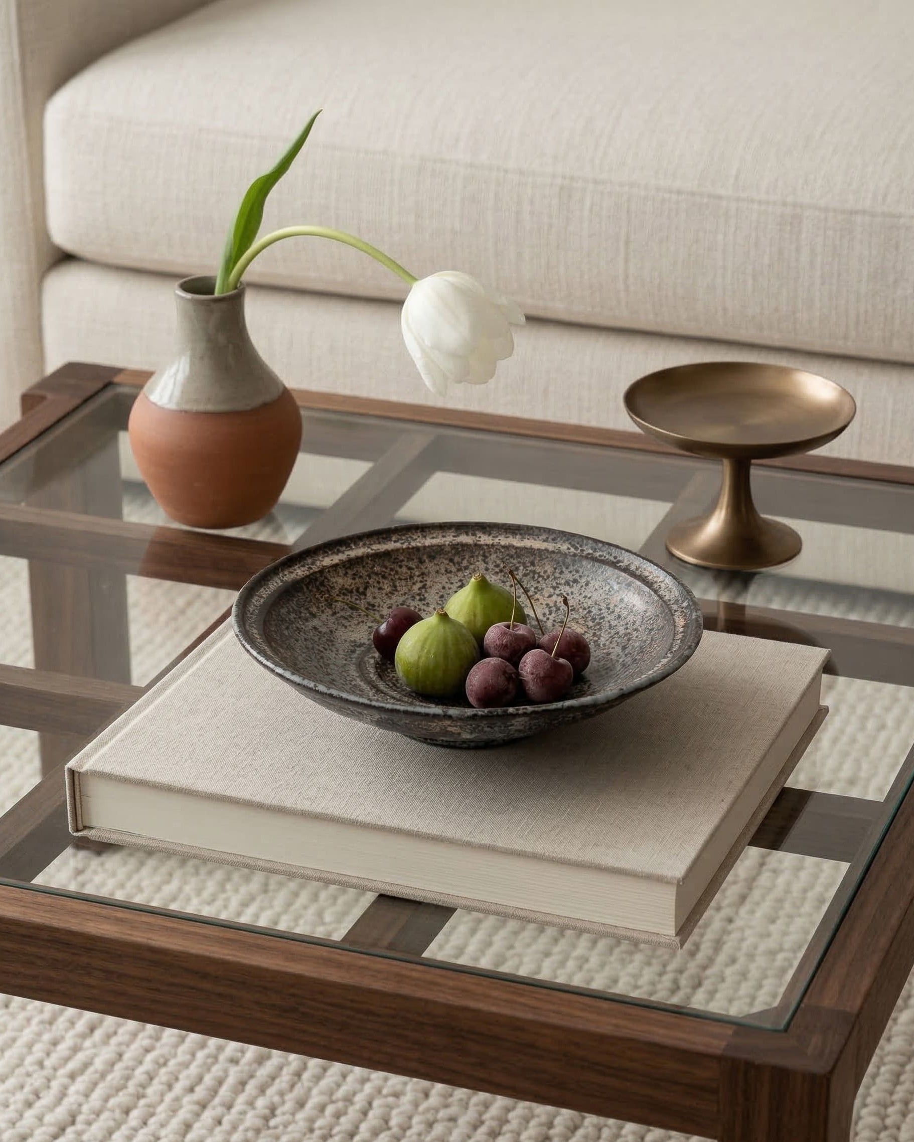Decorative setting on a coffee table with a bowl of fruit, vase, and books.