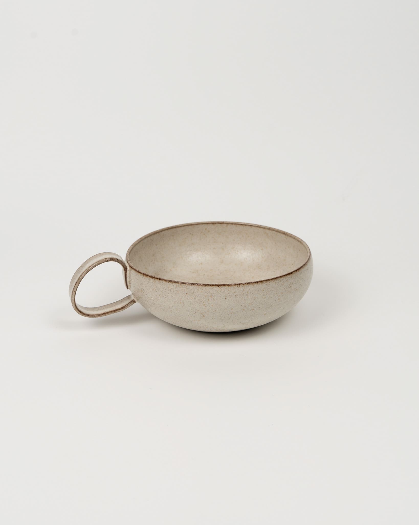 Ceramic cup with handle on a light gray background