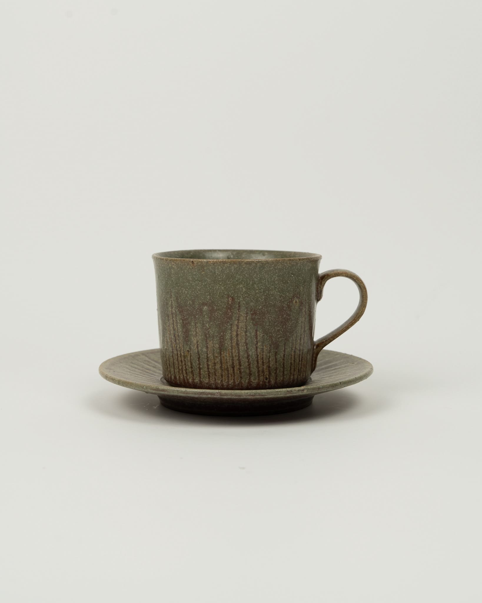 Green ceramic cup and saucer on a light gray background